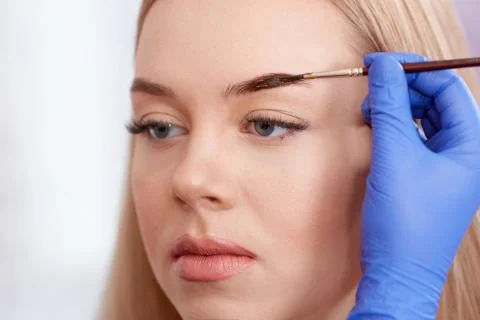 Cosmetologist making permanent eyebrows  using brus Stock Photos