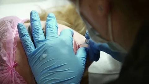 Cosmetologist making the permanent makeup for a young woman closeup Stock Footage 74214620