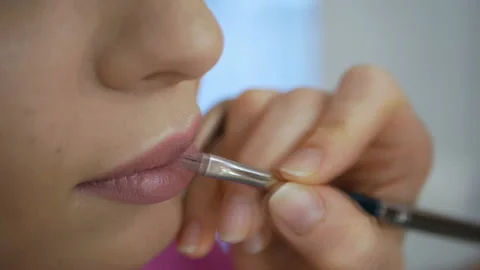 Cosmetologist paints lips model. Makeup for a young girl Stock Footage 120543568