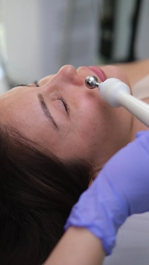 Cosmetologist performing a micro current therapy facial rejuvenation treatment Stock Footage 318369781