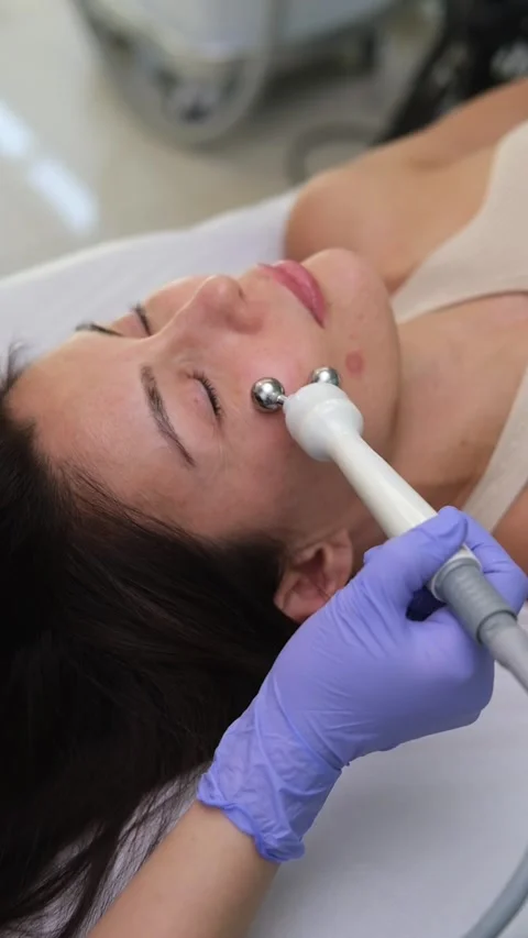 Cosmetologist performing a micro current therapy facial rejuvenation treatment Stock Footage 318647300