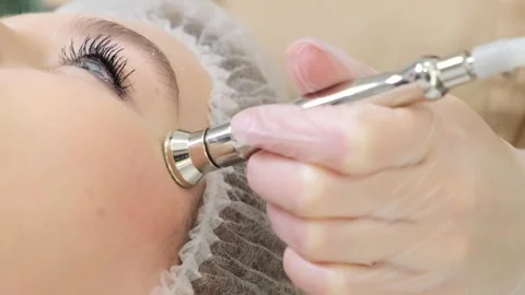 A cosmetologist performs an anti-aging procedure on the forehead of a beautiful Vídeo Stock 252684379