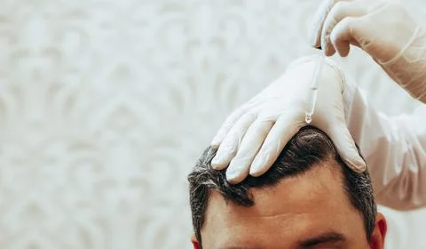 A cosmetologist performs anti-aging procedures, applies hyaluronic acid serum to Stock Photos