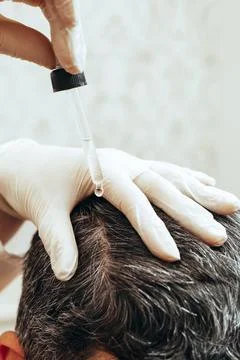 A cosmetologist performs anti-aging procedures, applies hyaluronic acid serum to Stock Photos