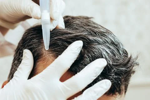 A cosmetologist performs anti-aging procedures, applies hyaluronic acid serum to Stock Photos