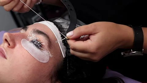 A cosmetologist performs an eyebrow shaping procedure on a model. At a salon Stock Footage 320083196