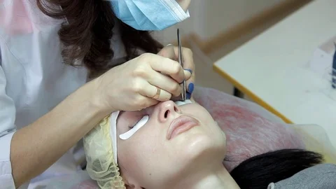The cosmetologist performs eyelash extensions to the client. Update the Stock Footage 84574999
