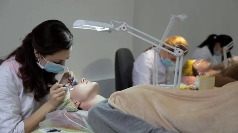 The cosmetologist performs eyelash extensions to the client. Update the Stock Footage 84586351