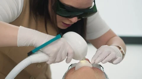 A cosmetologist performs a hardware procedure on a woman's face. Stock Footage 303443405