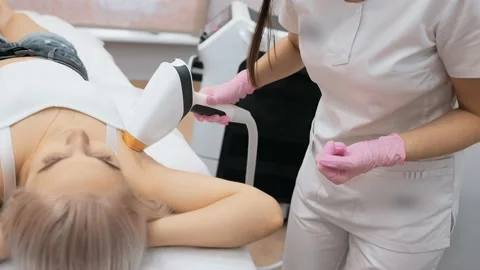 Cosmetologist performs laser epilation of the armpits of a young female patient Stock-Footage 232619492