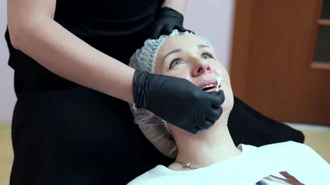 A cosmetologist performs a lip augmentation procedure in a beauty salon Stockbeeldmateriaal 264684628