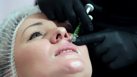 A cosmetologist performs a lip augmentation procedure in a beauty salon Stockbeeldmateriaal 264684992