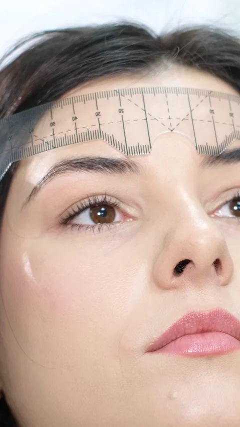 A cosmetologist performs a permanent eyebrow make-up procedure using a special Stock-Footage 250440036