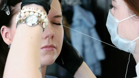 Cosmetologist performs the procedure of correction eyebrow threading. Side view. Stock Footage 86917188