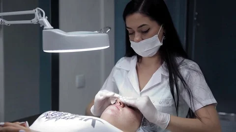 The cosmetologist processes the face of the customer after the procedure of Stock Footage 81107779