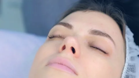 Cosmetologist separates woman's lashes using tweezers after laminating. Stock Footage 136875199