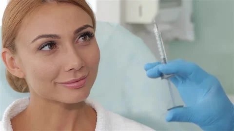 Cosmetologist shows injection to the client Stock Footage 248906025