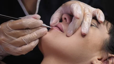 A cosmetologist uses a brush to create the contour of a woman's lips. Stock Footage 278222279