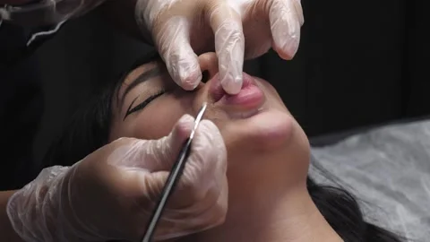A cosmetologist uses a brush to create the contour of a womans lips. Stock Footage 346442153
