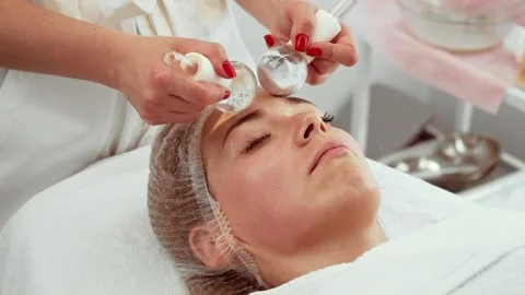 Cosmetologist using cooling massage spheres on woman face in skin studio. Female Stock Footage 324507203