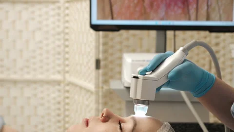 Cosmetologist using skin analysis device on forehead during facial treatment. Stock-Footage 321577181