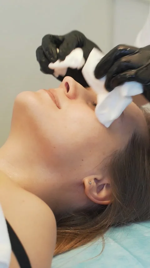 Cosmetologist wipes young woman's face with wet white sponges from dirt. She Vídeo Stock 169009853