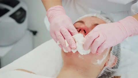 Cosmetologist wiping client face during skincare procedure. Professional Stock Footage 312038341