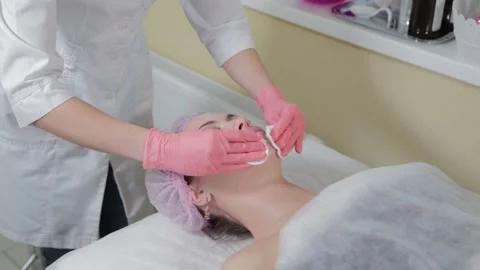 Cosmetologist's hands wiping eyebrows using cotton pads. Beautician rubs client 库存影片 152290336