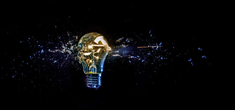 Cosmic explosion of a burning light bulb with flying splinters and smoke on a Stock Photos