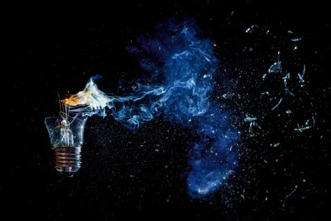 Cosmic explosion of a burning light bulb with flying splinters and smoke on a Stock Photos