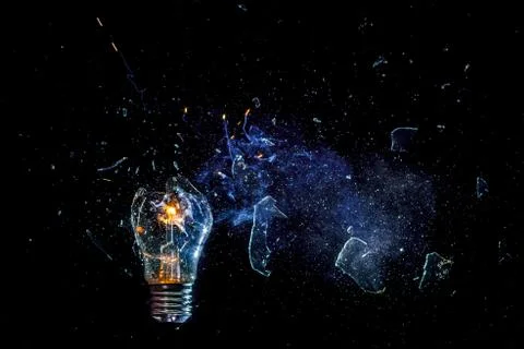 Cosmic explosion of a burning light bulb with flying splinters and smoke on a Stock Photos