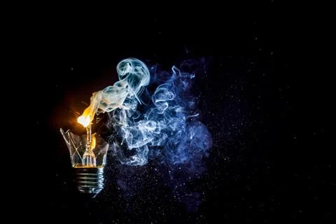 Cosmic explosion of a burning light bulb with flying splinters and smoke on a Stock Photos