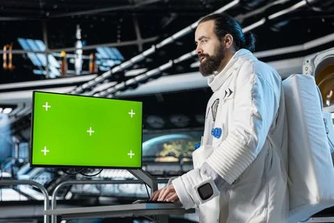 Cosmonaut verifying navigation coordinates on green screen monitor Stock Photos