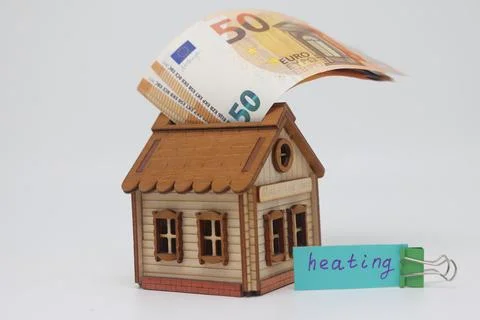 Cost concept for expensive utilities with a model of a wooden house and bankn Stock Photos