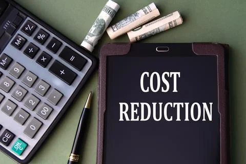 COST REDUCTION - words in an electronic notebook on the background of a cal.. Stock Photos