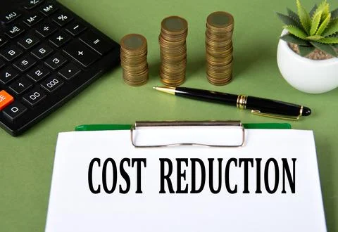 COST REDUCTION - words on a white sheet with a calculator and stacks of coins Stock Photos