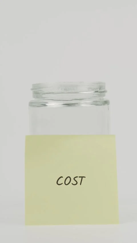 Cost text or word on yellow sticky note attached to glass jar with hand Stock Footage 311700778