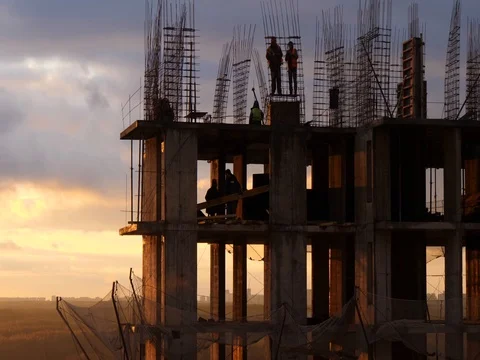 Costruction site against cloudy sunset sky. Workers among rebar rods and Stock-Footage 85054045