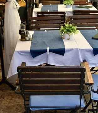 Cosy Outdoor Cafe Table Setting with Blue Table Runners and Wooden Chairs Stock Photos