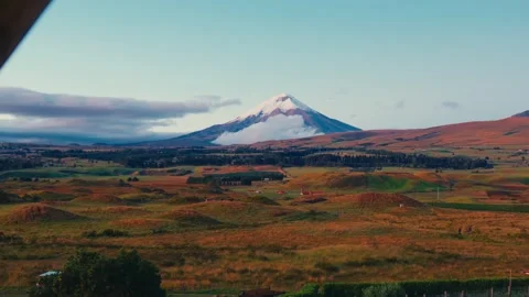 Cotopaxi volcano rises above clouds over rolling hills and farmland in Ecuador Stock Footage 345156482