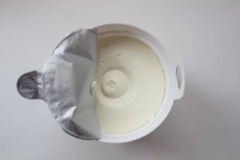 Cottage cheese in a container on a white background. Stock Photos