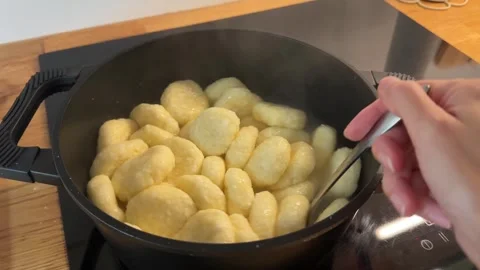 Cottage Cheese Dumplings Boiling in Pot and Stirred with Spoon Stock Footage 344602225