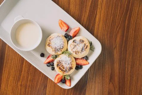 Cottage cheese pancakes with strawberries on a rectangular plate with sauce on a Stock Photos
