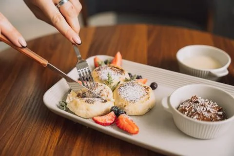 Cottage cheese pancakes with strawberries on a rectangular plate with sauce on a Stock Photos