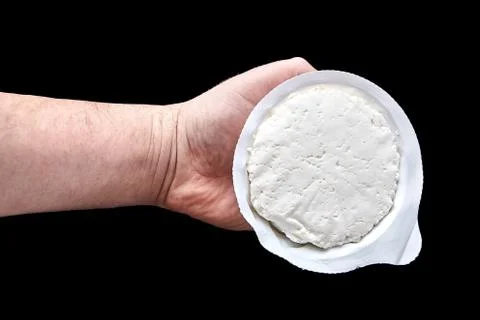 Cottage cheese in plastic packaging lying on the hand Stock Photos