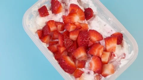 Cottage cheese with strawberries in a plastic container on a blue background Stock Footage 150899242