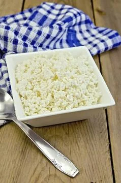 Cottage cheese in a white square bowl, a blue checkered napkin, spoon on a Stock Photos