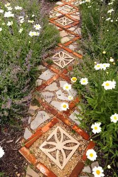 Cottage Garden Path with Bricks and Stone Pavers Surrounded by Daisies and Ca Stock Photos