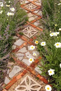 Cottage Garden Path with Bricks and Stone Pavers Surrounded by Daisies and Ca Stock Photos