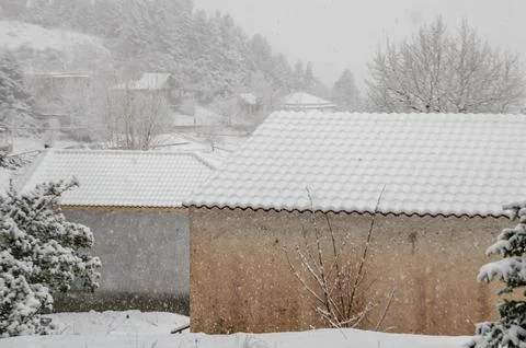 Cottage Rooftops Covered with Snow in a Small Mountain Village During Blizzard 写真素材